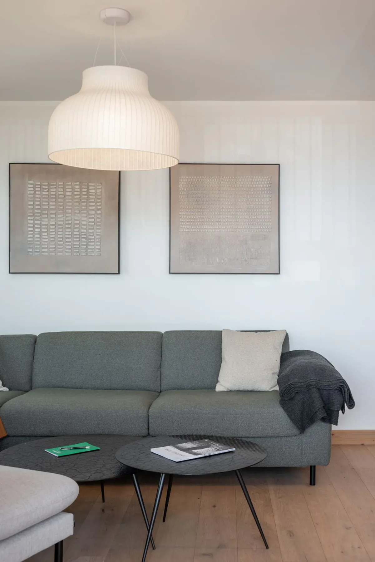 Modern living room with large windows, gray sectional sofa, armchair, coffee table, wall-mounted TV, and scenic mountain view.