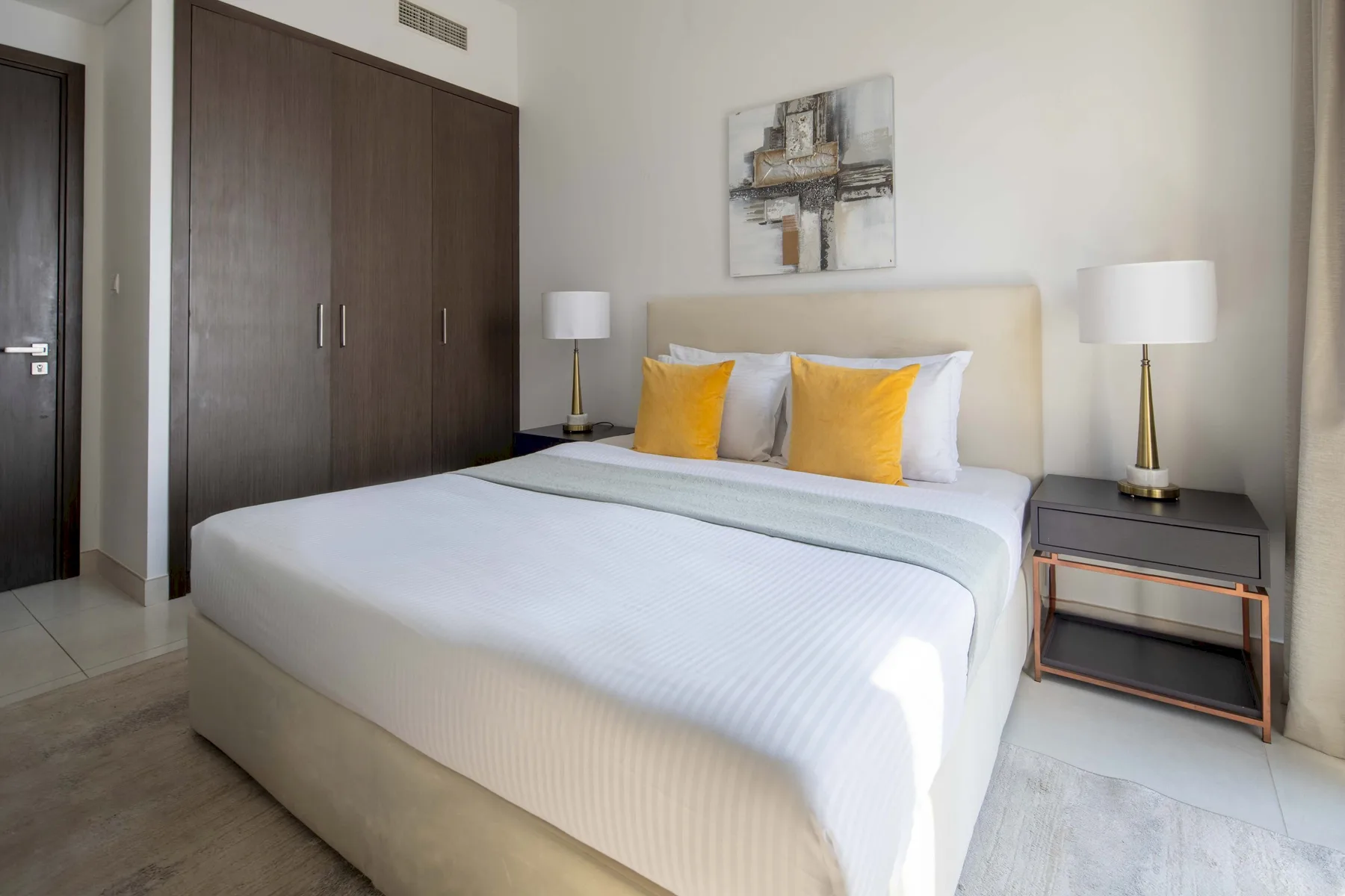 Un dormitorio con una cama grande, cojines amarillos y lámparas de mesilla.
