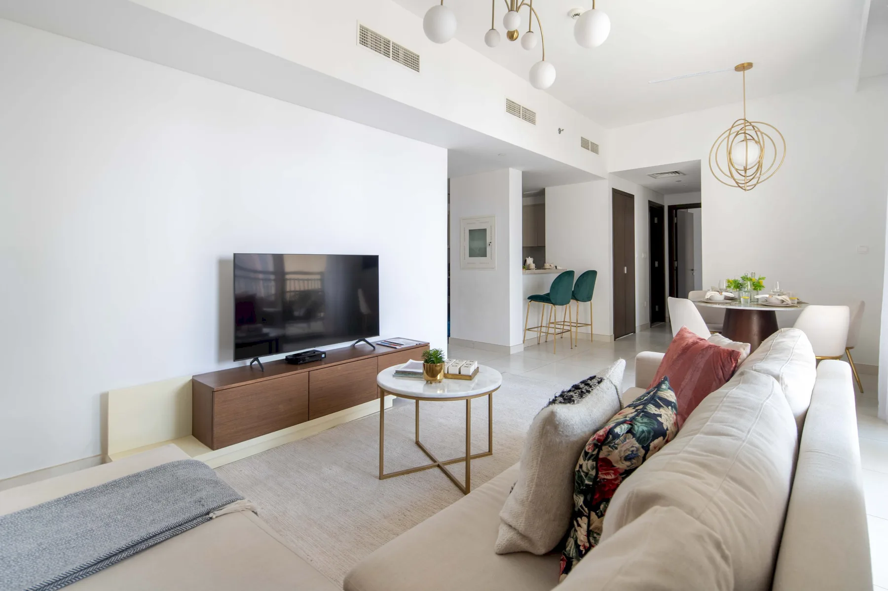 Una sala luminosa con televisor, asientos y un comedor.