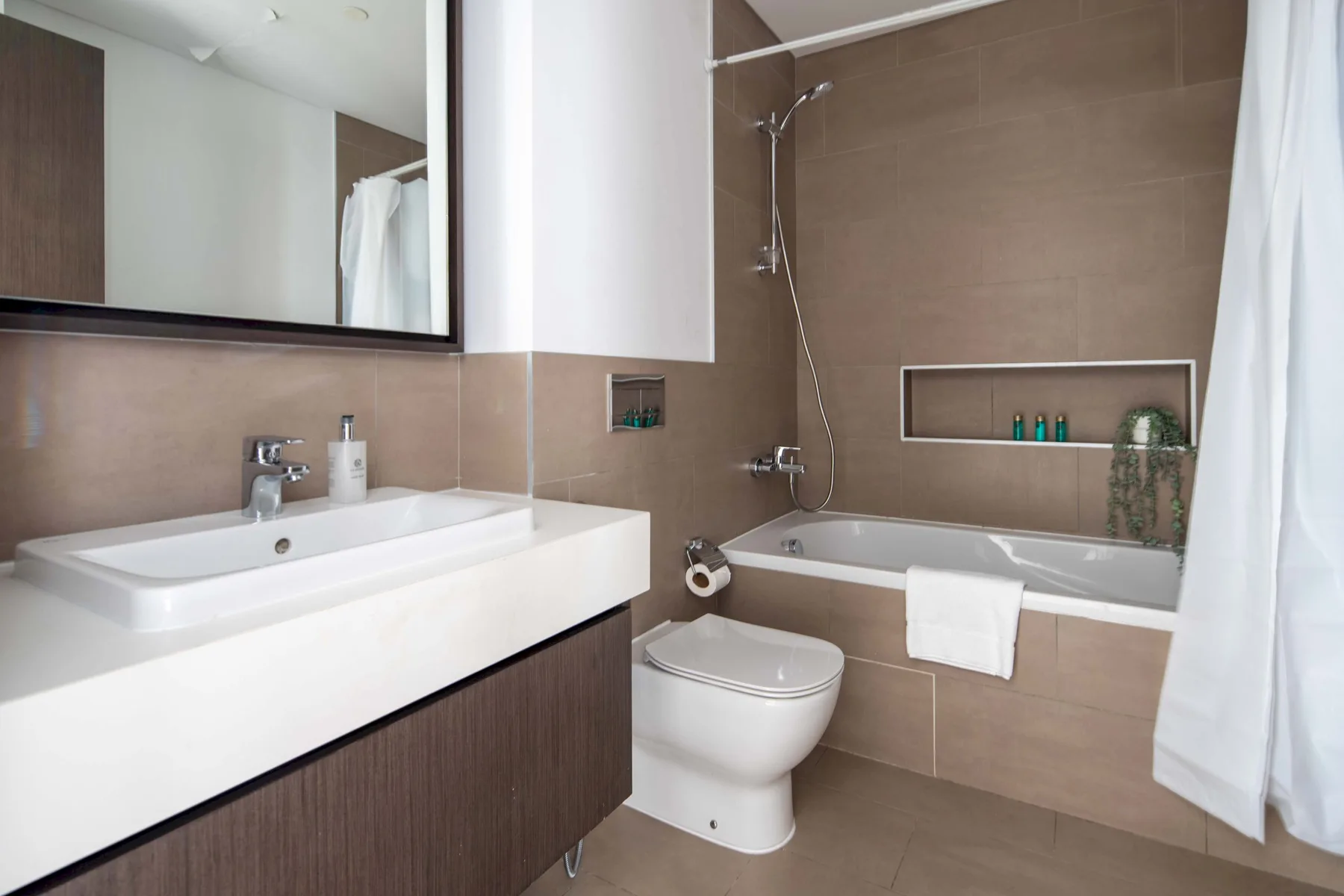 Un baño con lavabo, inodoro y bañera bajo una ducha de pared.