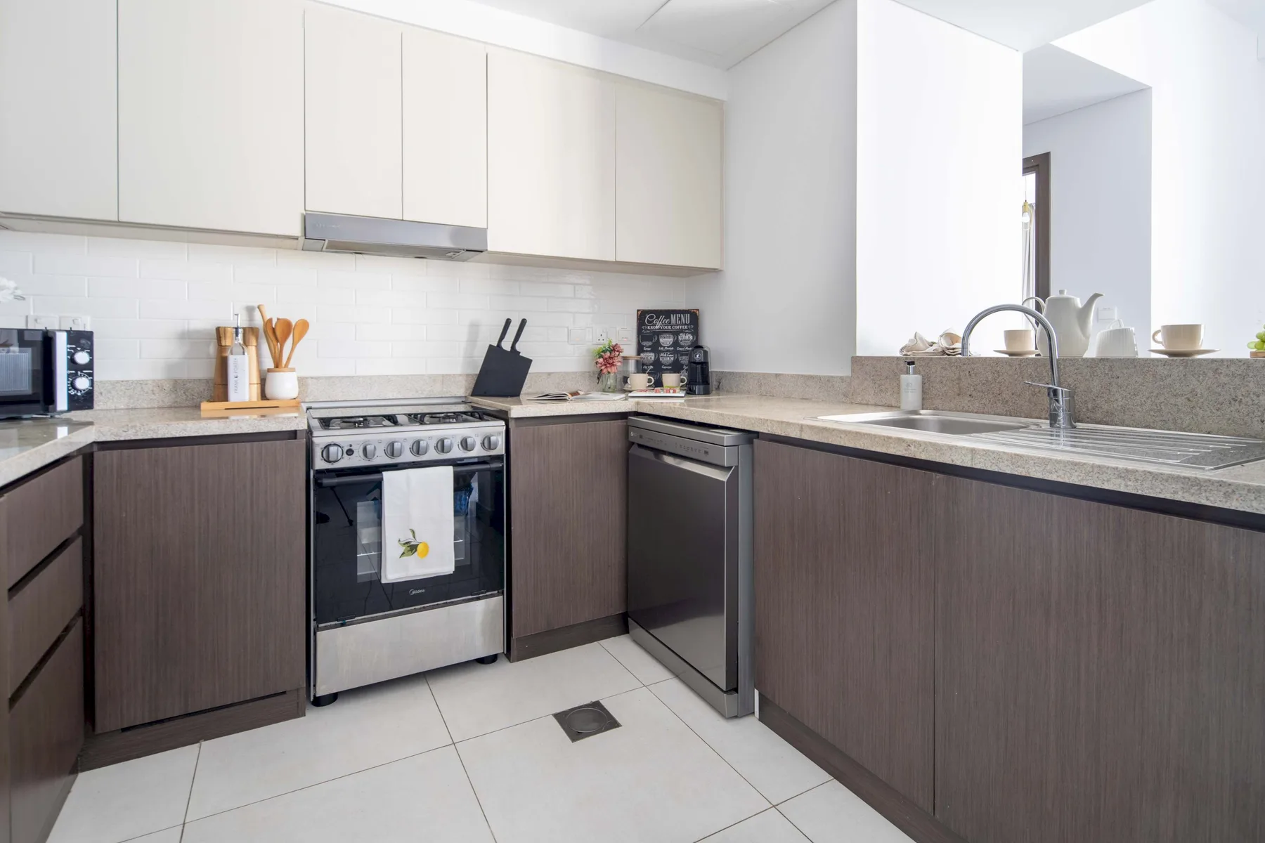 Una cocina moderna y luminosa con gabinetes inferiores oscuros y una estufa de acero inoxidable.