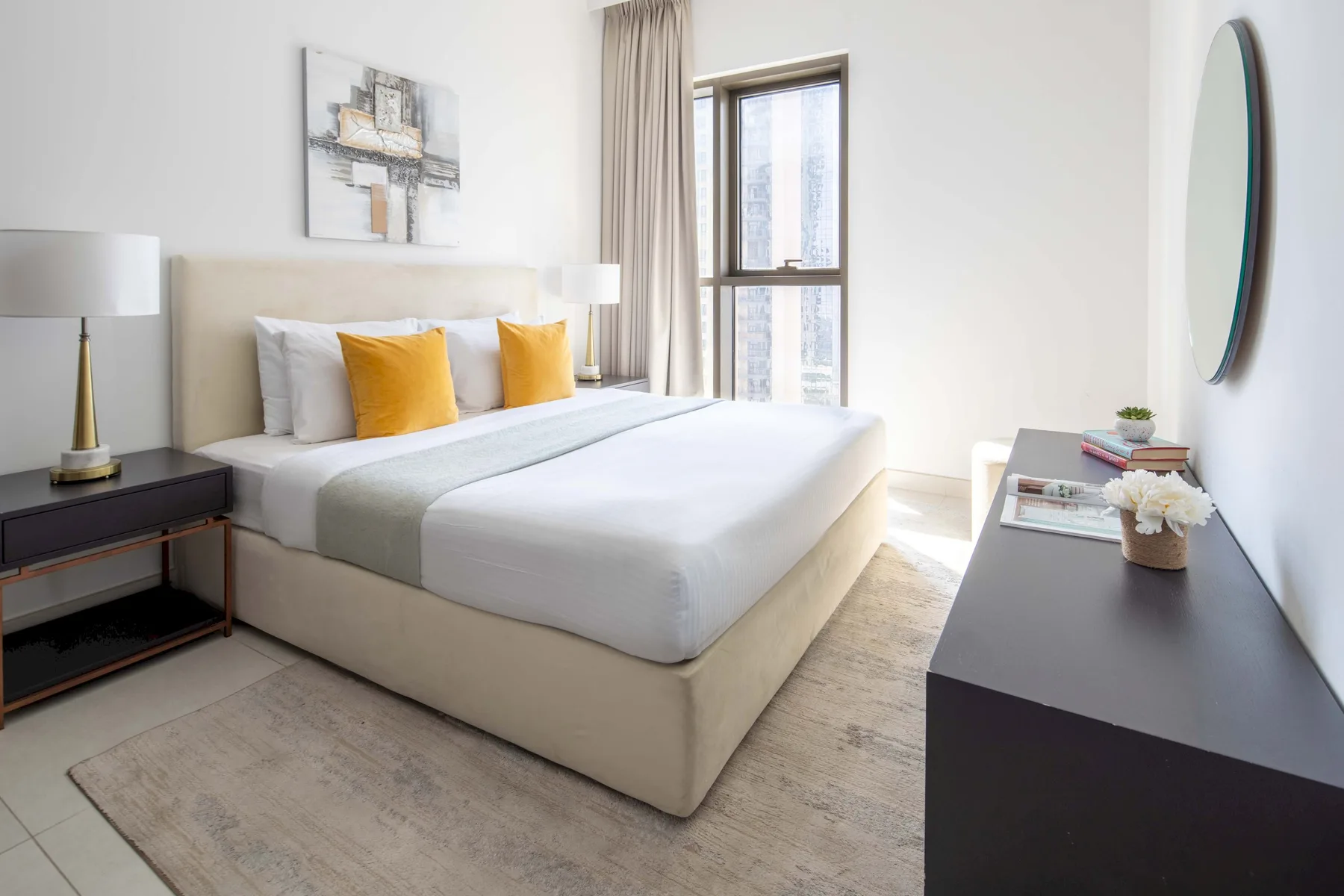 Un dormitorio luminoso con una cama bien tendida y una ventana grande.
