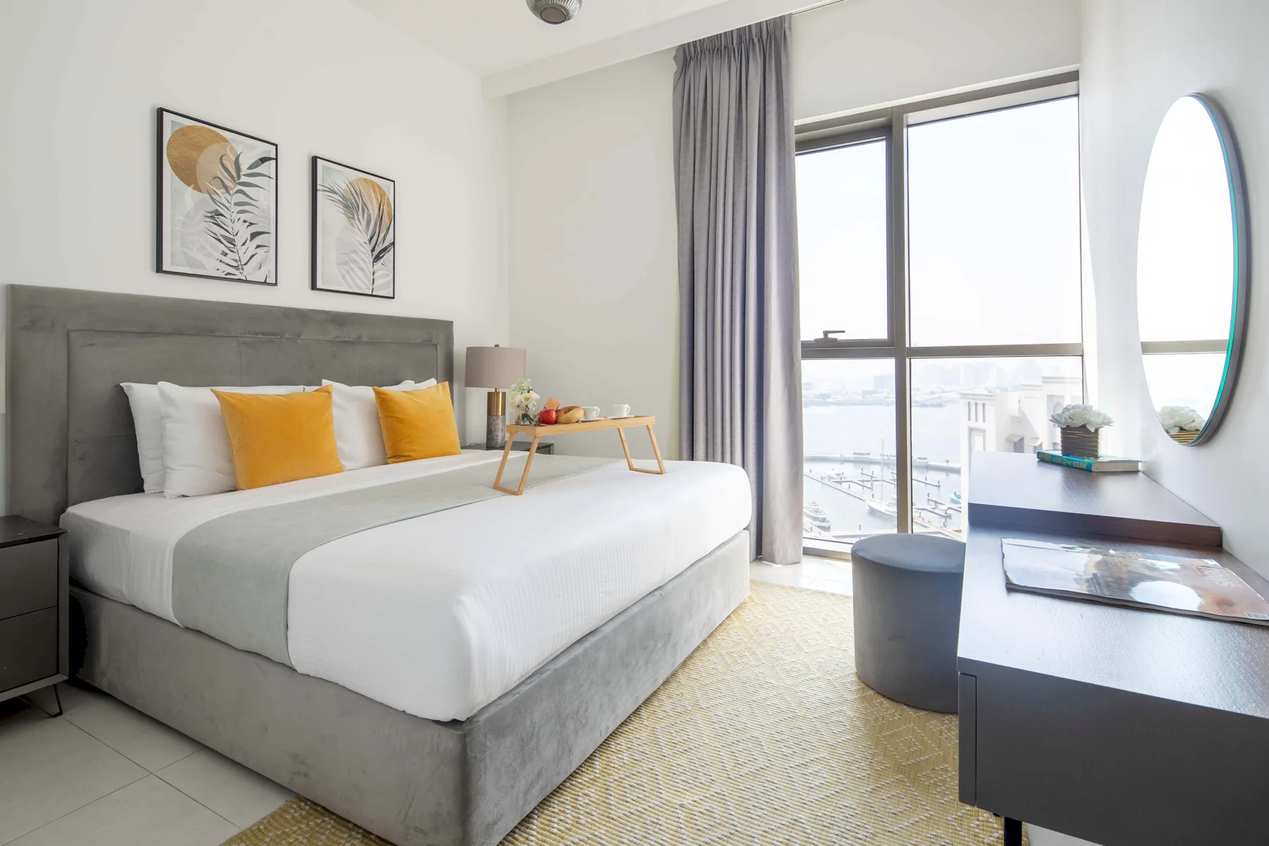 Un dormitorio luminoso tiene una cama grande junto a una ventana de piso a techo.
