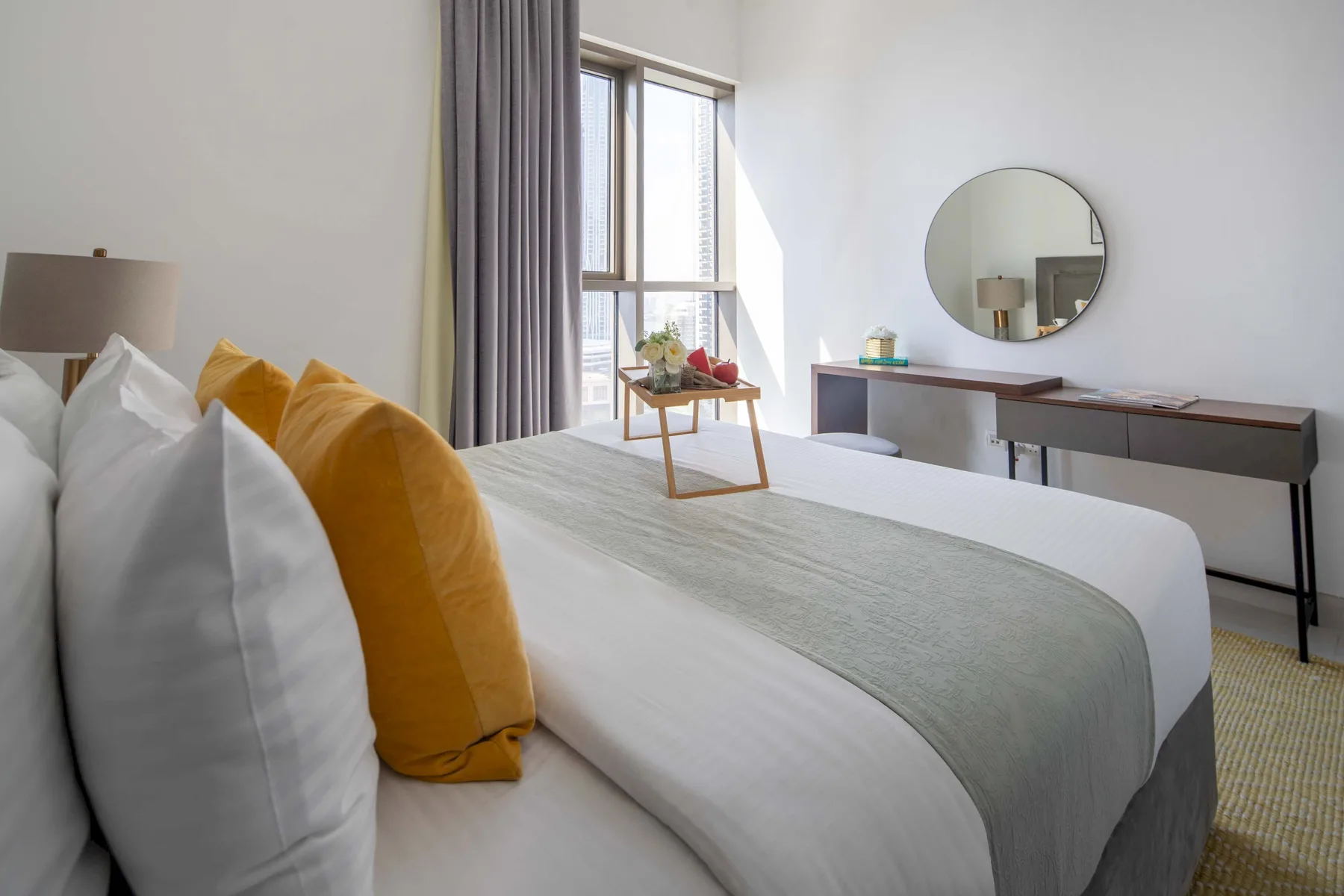 Un dormitorio luminoso con una cama tendida junto a una ventana alta.