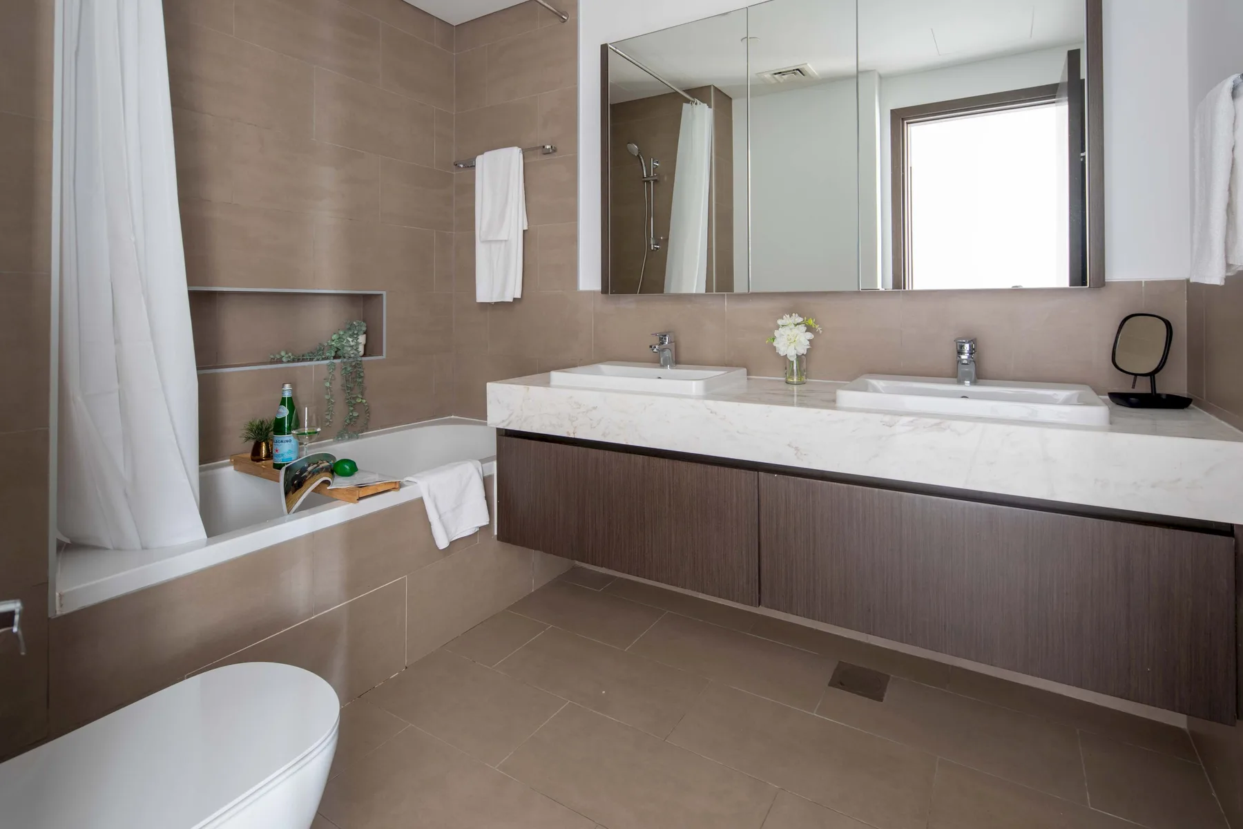 Un baño con bañera, lavabo doble y un espejo grande.