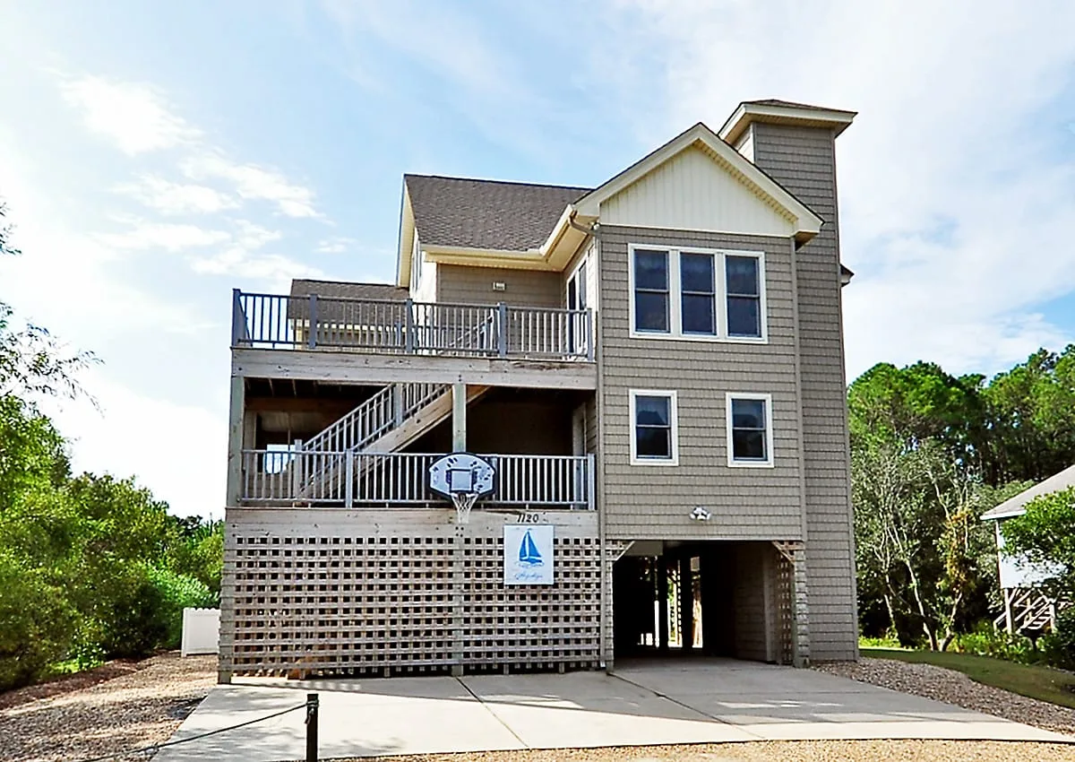 A raised multi-level house with open decks and a basketball hoop.