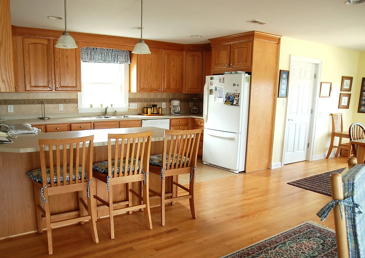 A kitchen and dining area with wooden cabinets, a refrigerator, and a table with chairs.