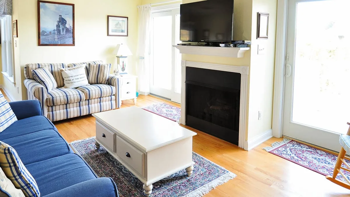 A bright living room with striped seating, a coffee table, and a fireplace.