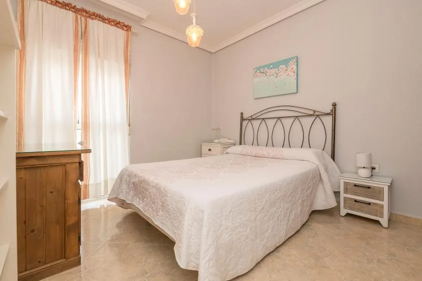 A bedroom with a bed, bedside tables, and a curtained window.