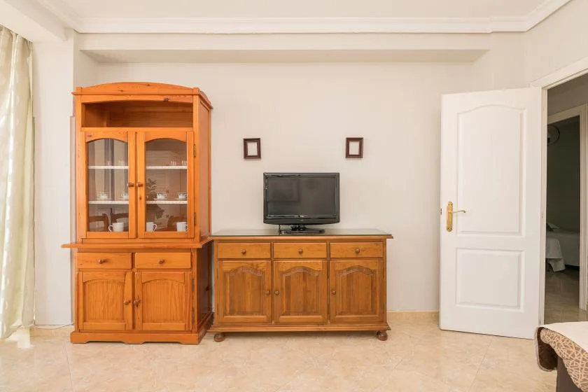 A living room with wooden cabinets and a television beside an open doorway.