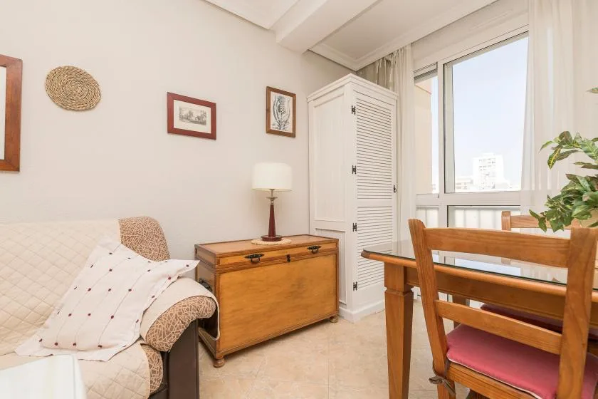 A bright sitting area with a cushioned seat beside a wooden dining table.