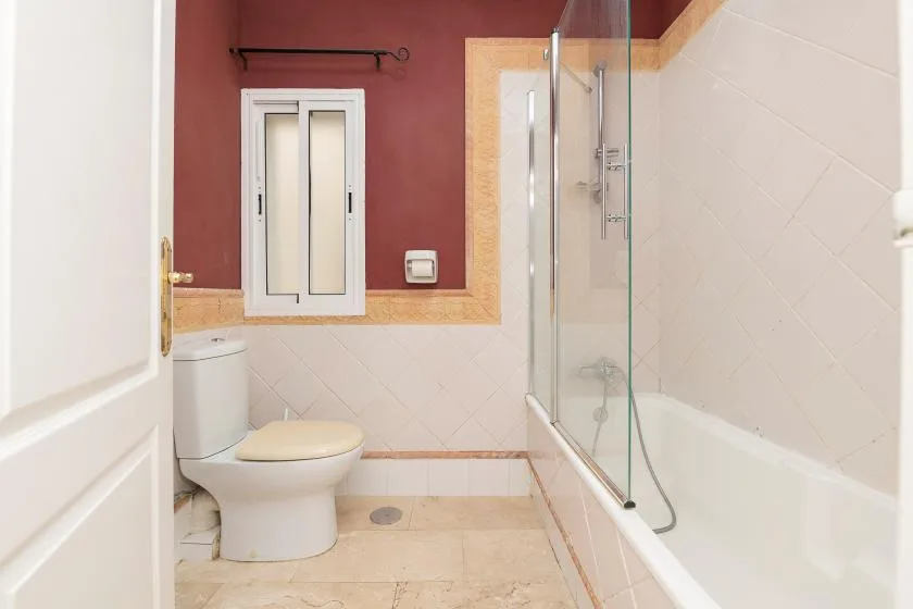 A bathroom with a toilet, bathtub, and glass shower screen.