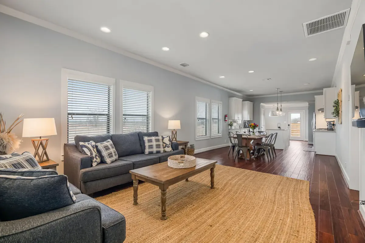 A living room with seating, a coffee table, and a dining area beyond.