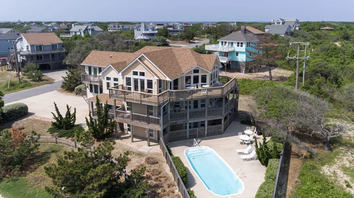 Una casa elevada junto a la costa, con piscina y vegetación alrededor.