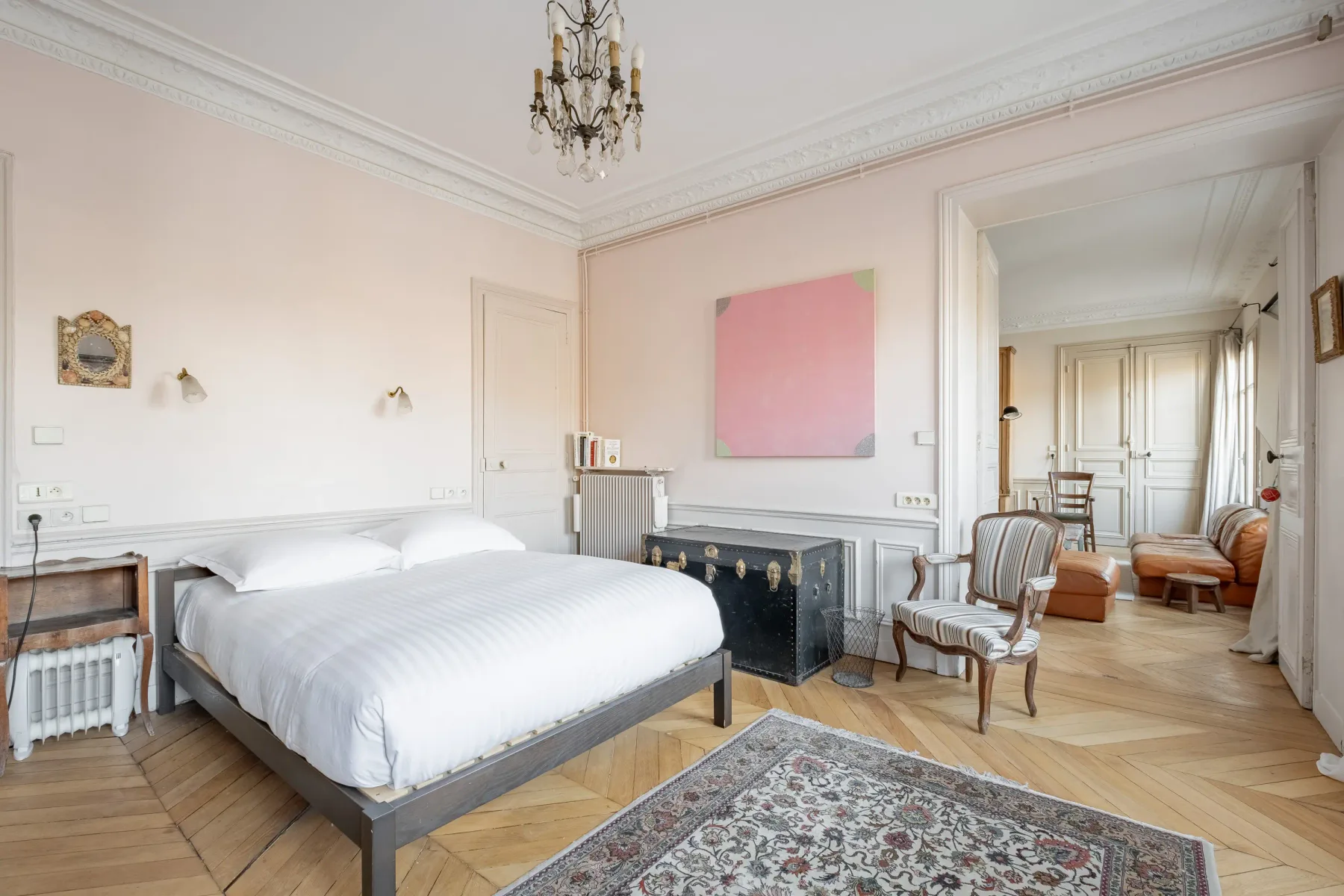 A bedroom with a large bed, a fireplace, and an adjoining sitting area.