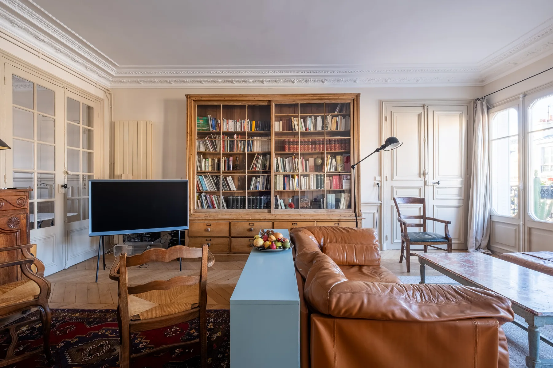 A living room with a bookcase, television, and leather seating.