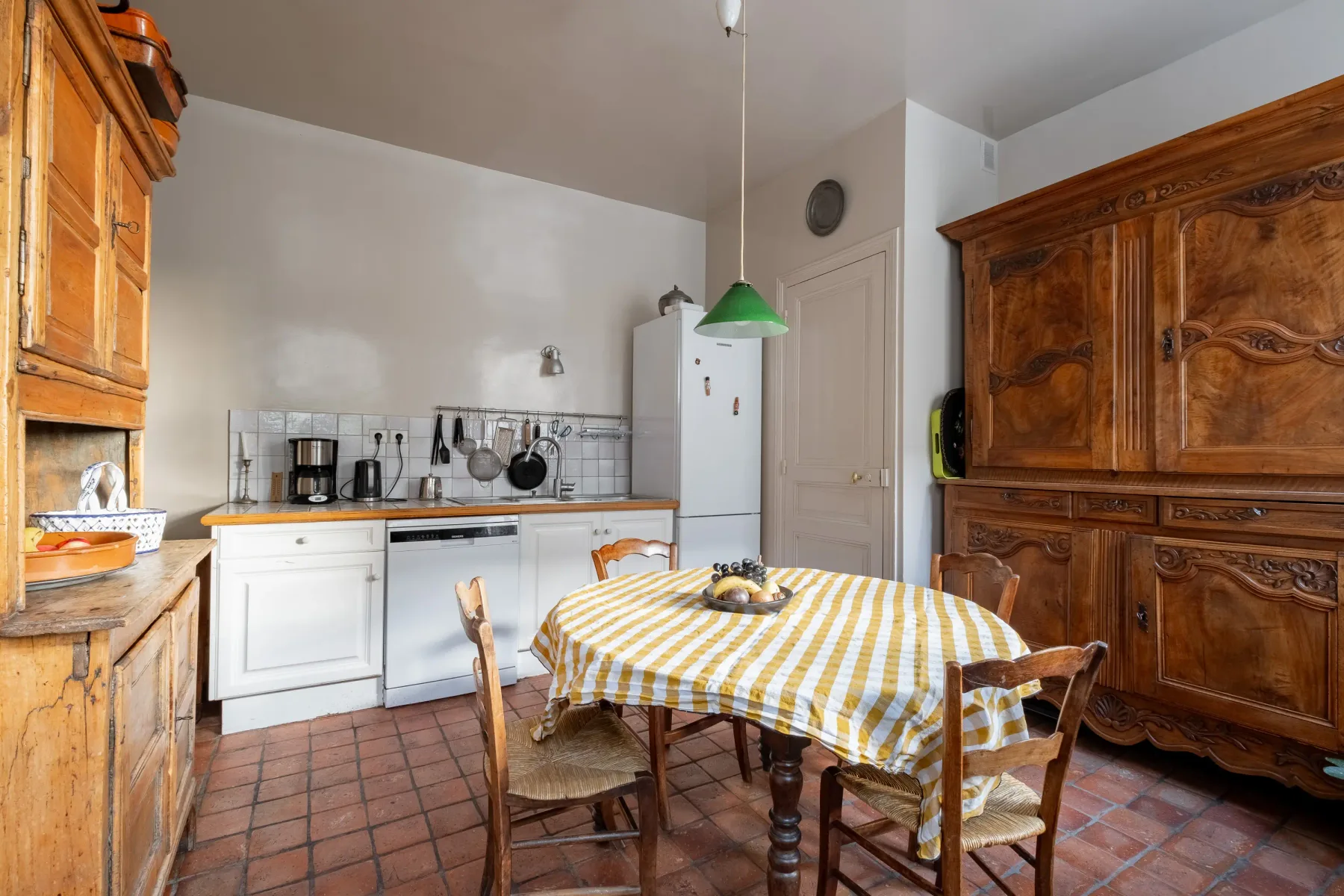 A kitchen and dining area with a checkered tablecloth and wooden cabinets.