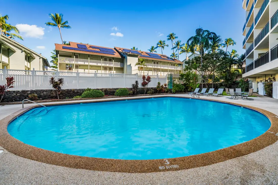 Una piscina al aire libre está junto a edificios y palmeras.