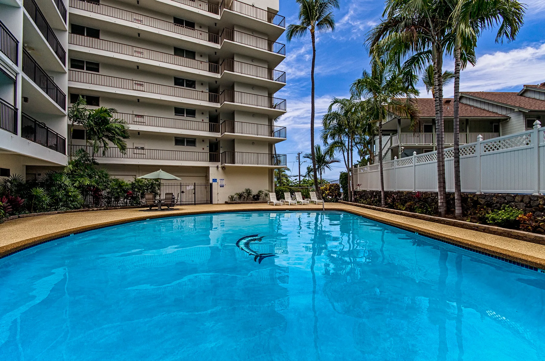 Una piscina al aire libre está junto a edificios de apartamentos y palmeras.