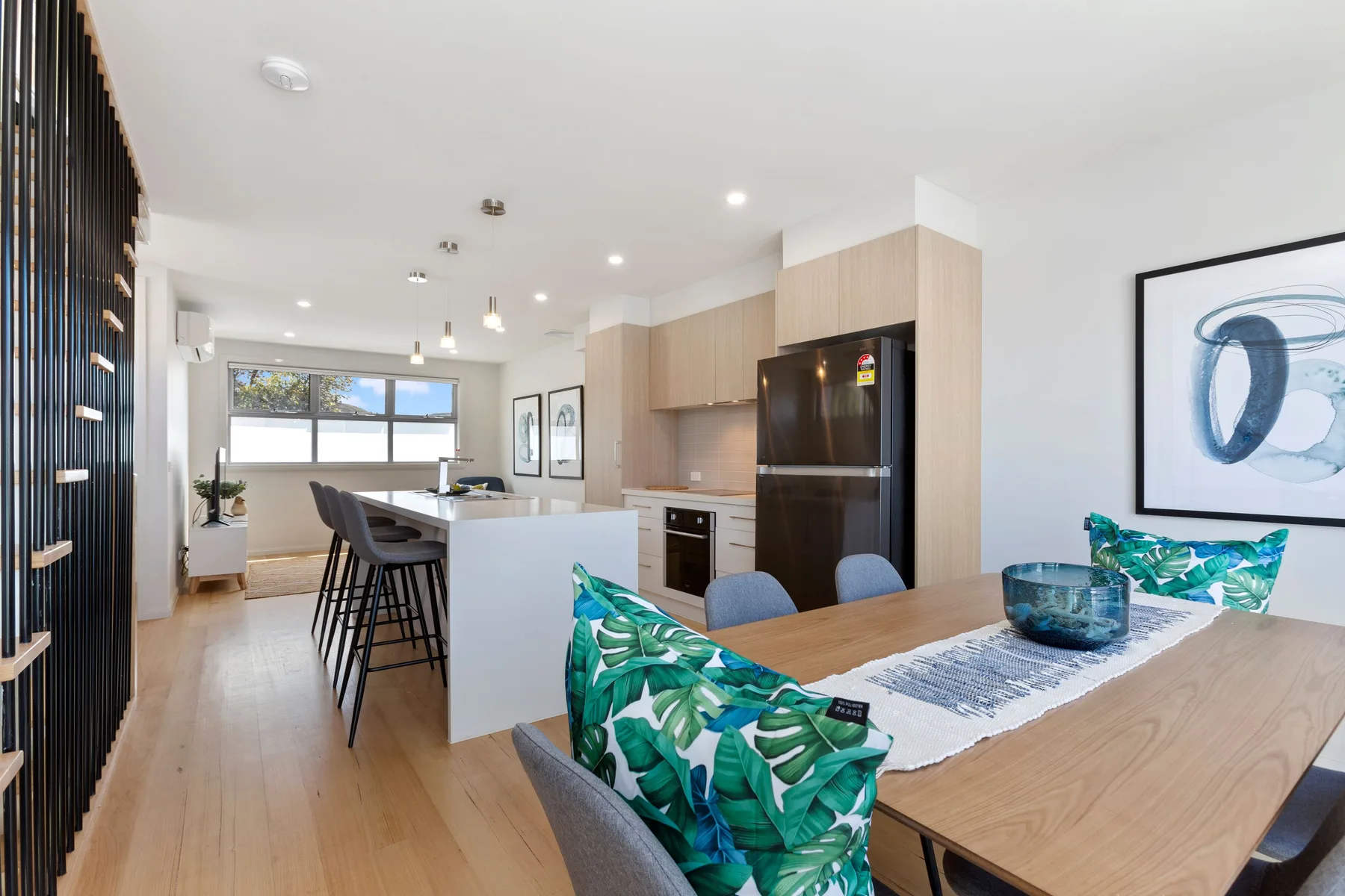 Cocina y comedor de planta abierta con una mesa de madera y asientos junto a la barra.