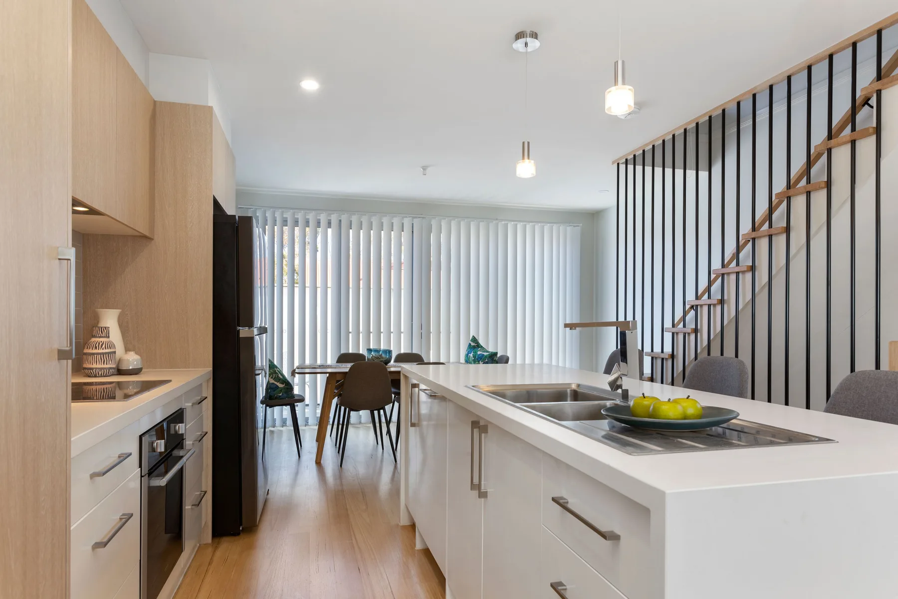 Una cocina moderna con una isla blanca alargada se abre a un comedor.