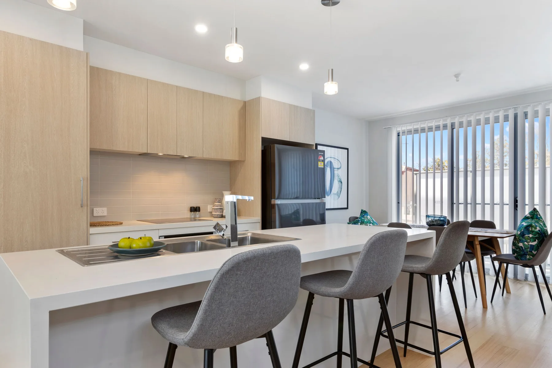 Una cocina y comedor luminosos con una barra larga y asientos altos.