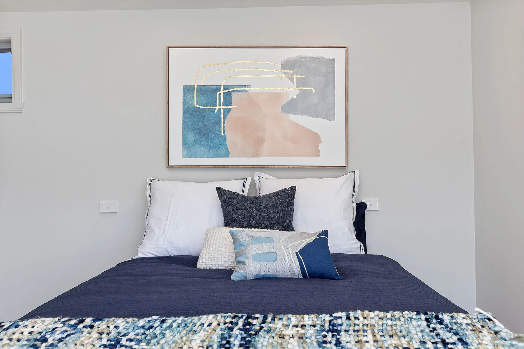Un dormitorio con una cama vestida con ropa de cama azul oscuro y almohadas.