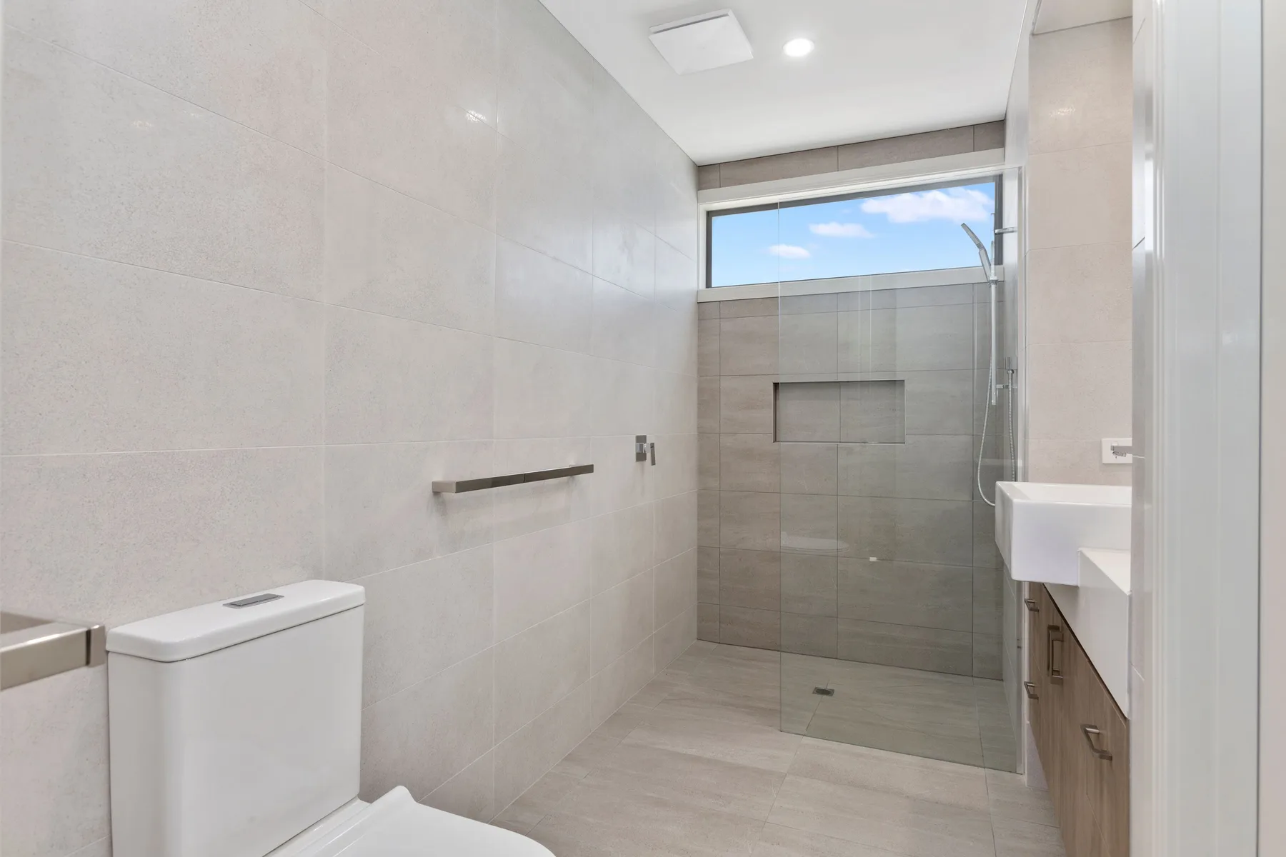 Un baño alicatado con una ducha de vidrio y un tocador al lado.