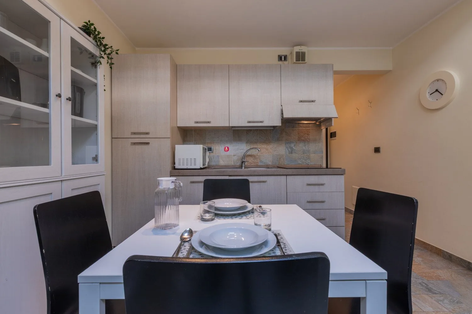 Un comedor con una mesa puesta junto a una cocina compacta.