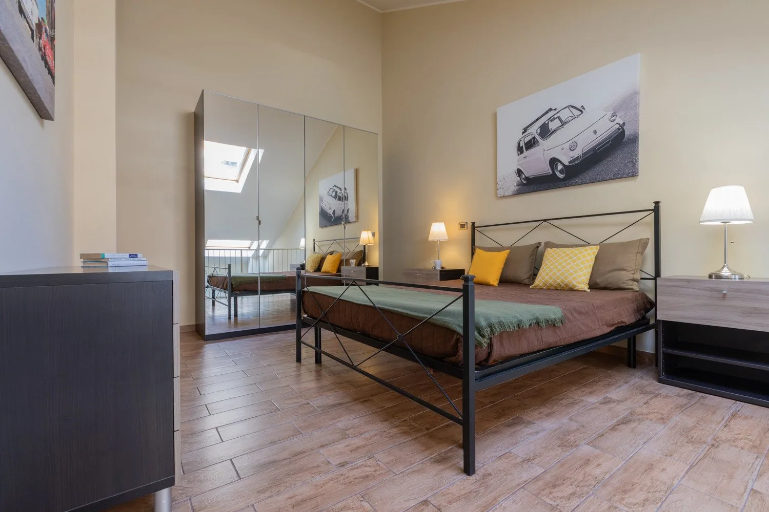 Un dormitorio con una cama de metal, almohadas de colores y puertas de armario con espejo.