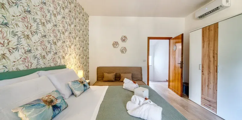 A bedroom with a bed, a small seating area, and an open doorway.