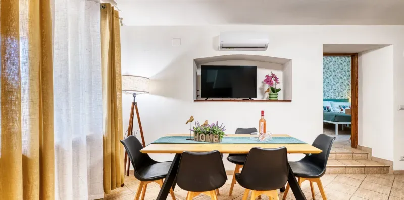 A dining area with a table and chairs, beside a doorway to a bathroom.