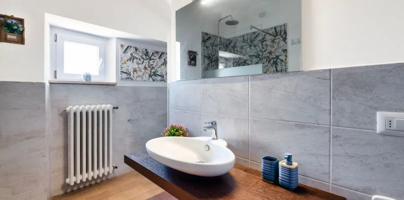 A bathroom with a wall-mounted sink, radiator, and glass shower screen.