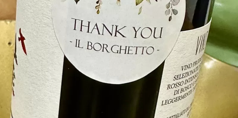 A close-up of a wine bottle with a round thank-you label.