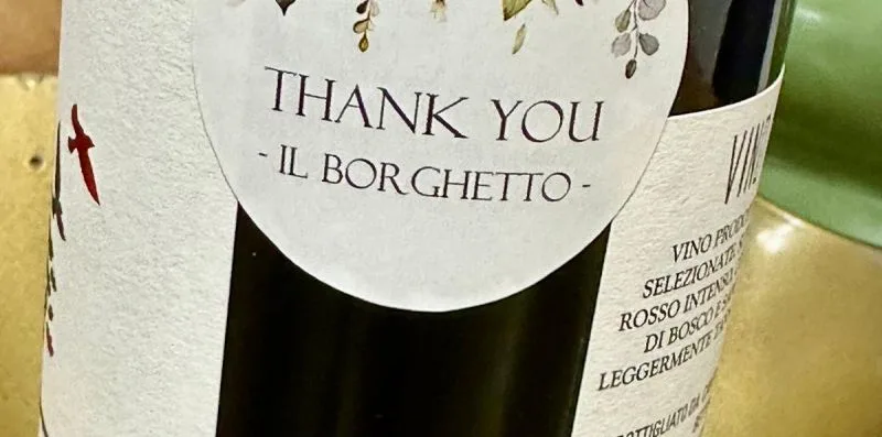 A close-up of a wine bottle with a round thank-you label.