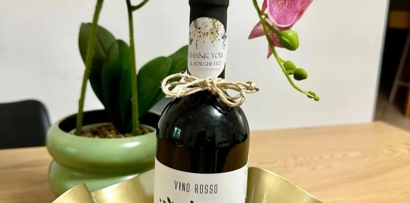 A wine bottle sits in a gold-colored tray beside a potted orchid.
