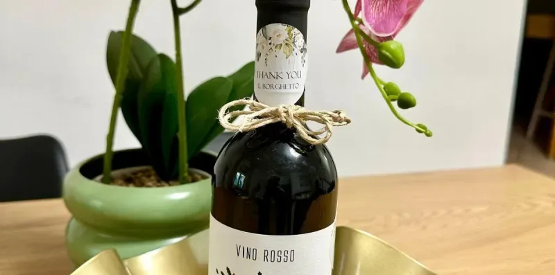 A wine bottle sits in a gold-colored tray beside an orchid.