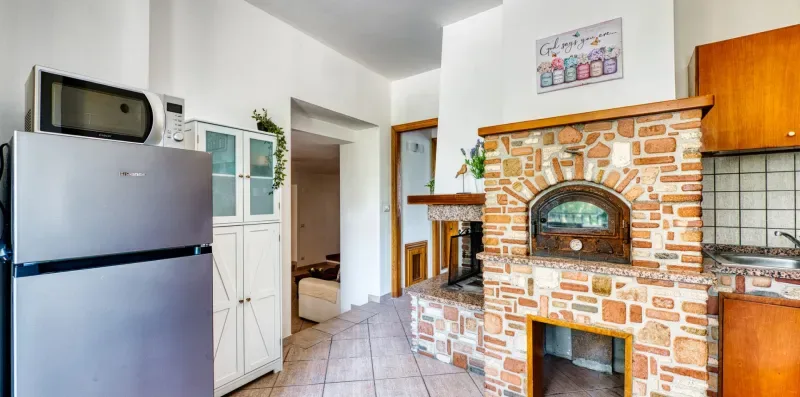 A kitchen with a brick fireplace and refrigerator.