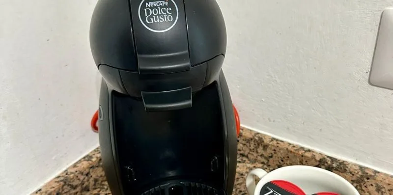 A coffee machine sits on a speckled countertop beside a cup.