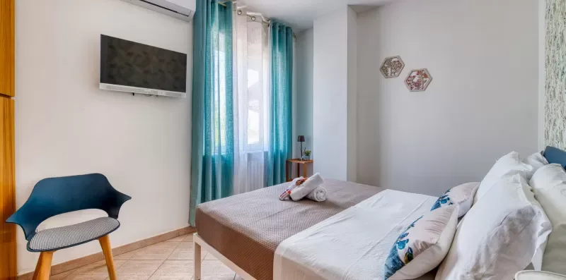 A bedroom with beds, teal curtains, and a wall-mounted television.