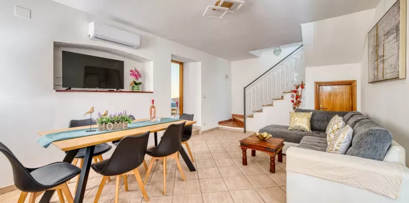 A dining and living area with a table, seating, and a staircase.