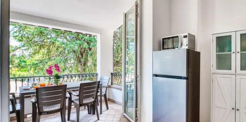 A dining area with a table and seating beside an open glass door.