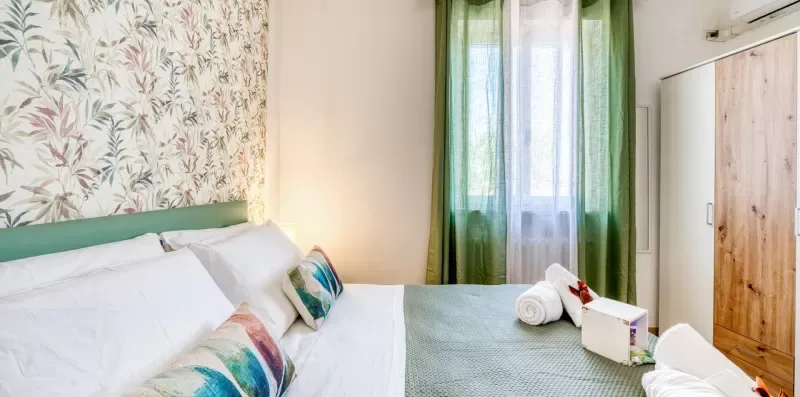 A bedroom with a bed, green curtains, and a wardrobe.