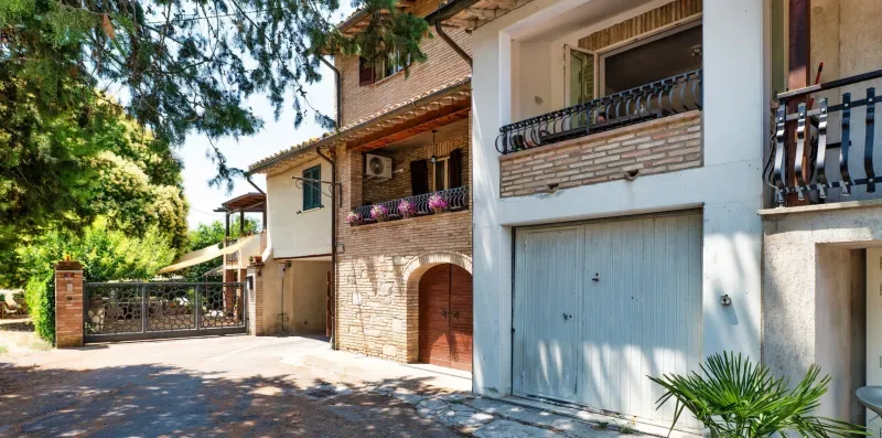 A sunny residential street with adjoining homes, balconies, and garage doors.
