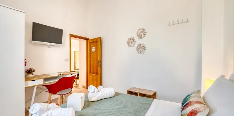 A bedroom with a bed, desk, and open wooden door.