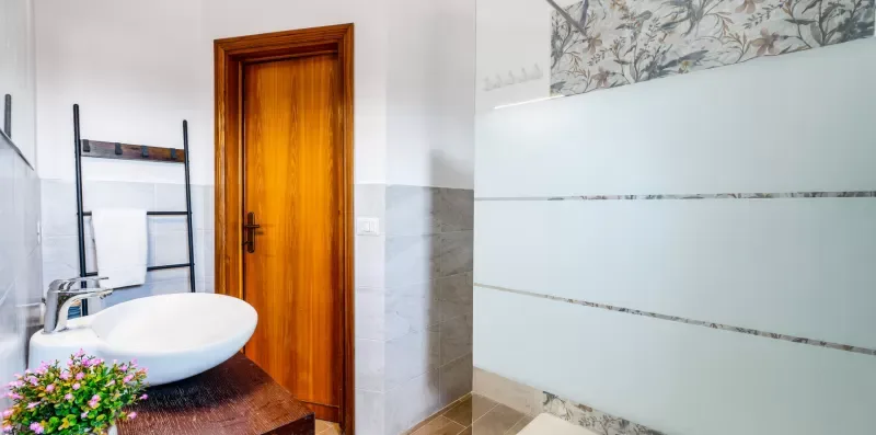 A tiled bathroom with a wooden door, sink, and wall-mounted towel rack.