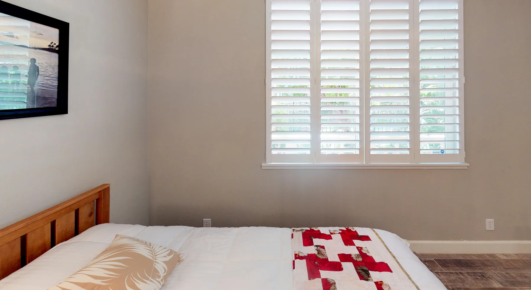 Dormitorio con una cama bajo una ventana con contraventanas blancas.
