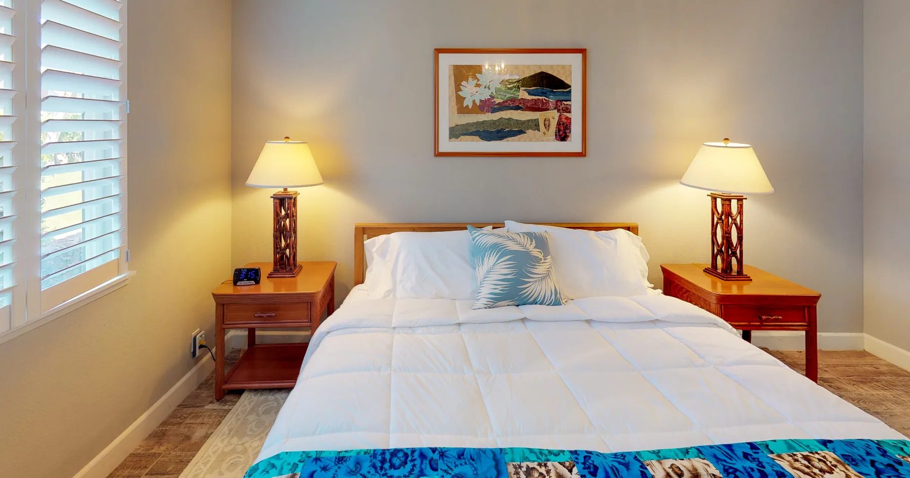 Un dormitorio con una cama bien tendida y mesas de noche a ambos lados.