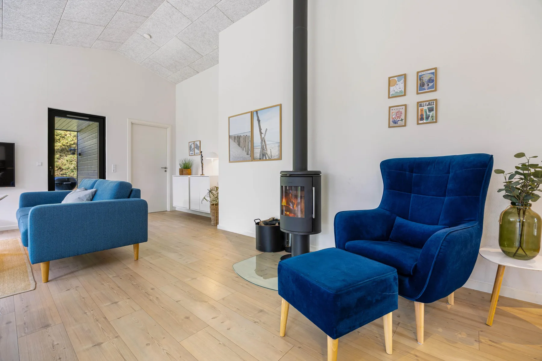 Una sala de estar luminosa con asientos azules y una estufa independiente.