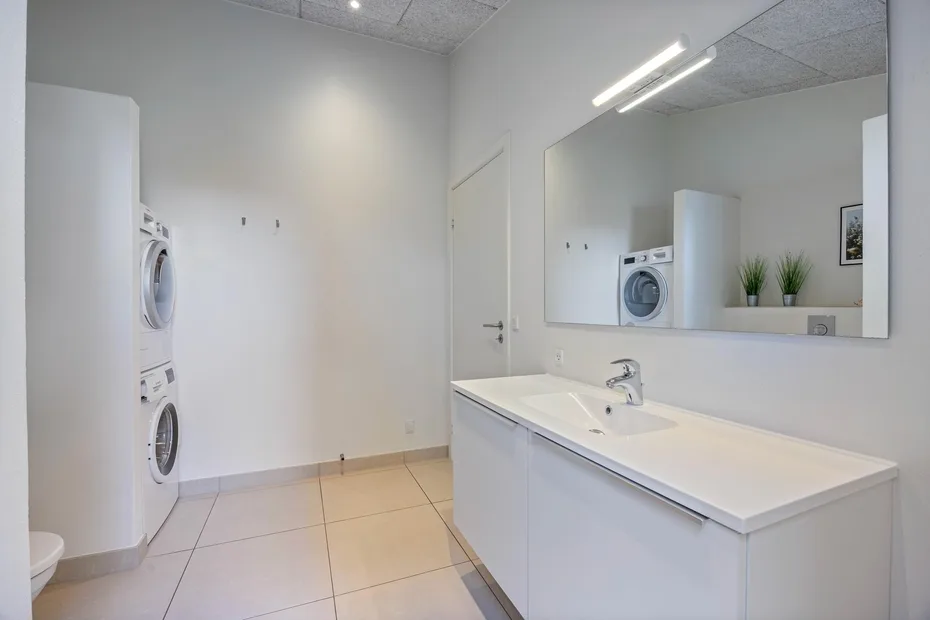 Un baño luminoso con un lavabo largo y un espejo grande en la pared.